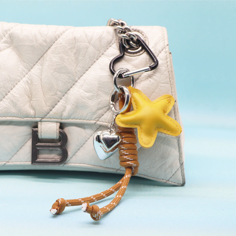 A stylish white leather purse adorned with a vibrant yellow star PU leather keychain, featuring a durable rope strap and silver heart charm.