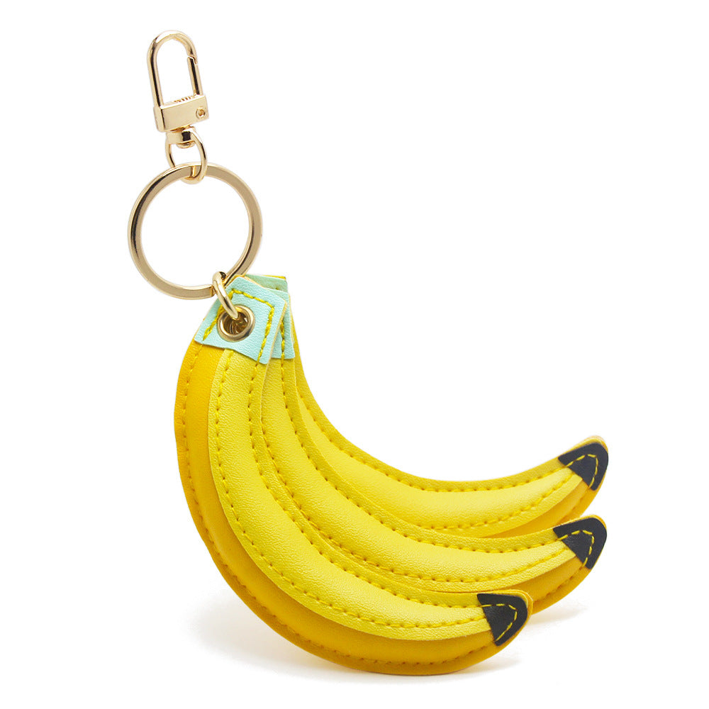 Wholesale cute banana keychain made of yellow PU leather, shaped like a bunch of three bananas with a gold metal clip for attaching to bags or purses.