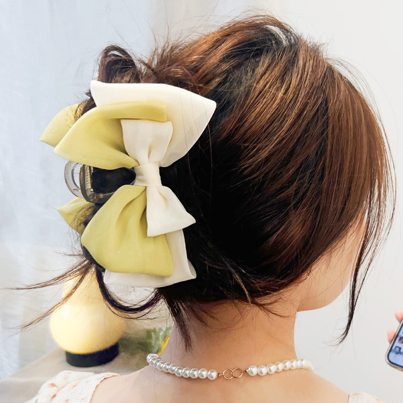 A close-up of a stylish two-layer, double-color fabric hair bow in yellow and white, attached to a plastic claw clip, from JR Fashion Accessories.