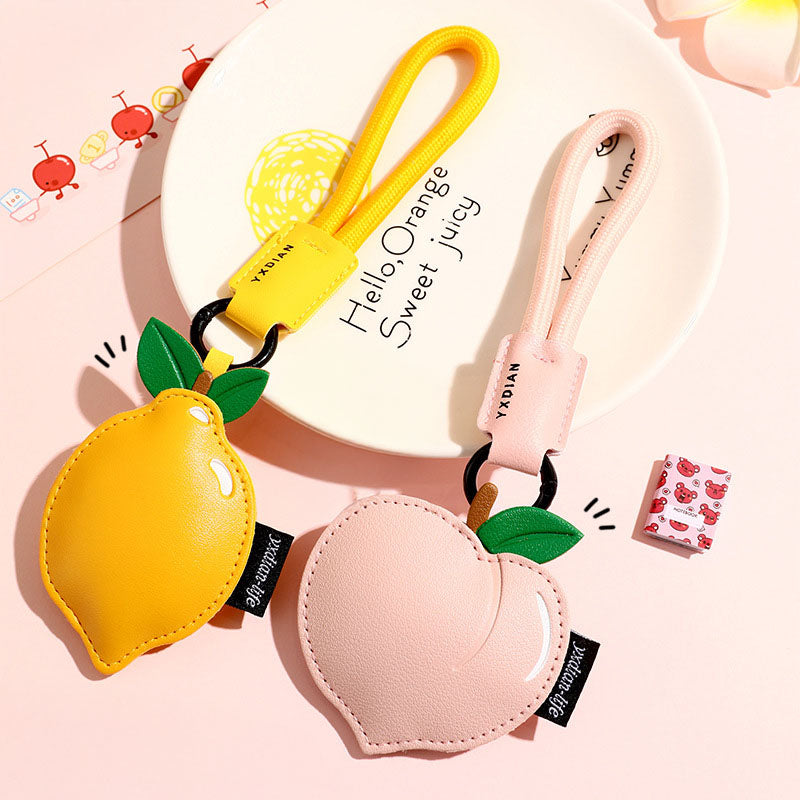 A pair of cute PU leather fruit keychain charms, one shaped like a yellow lemon and the other a pink peach, perfect as bag accessories.