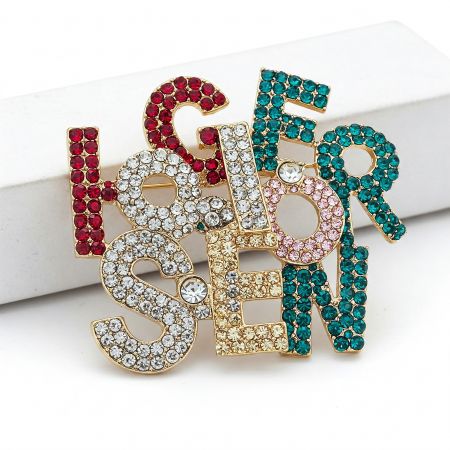 Модная брошь с буквами и стразами.