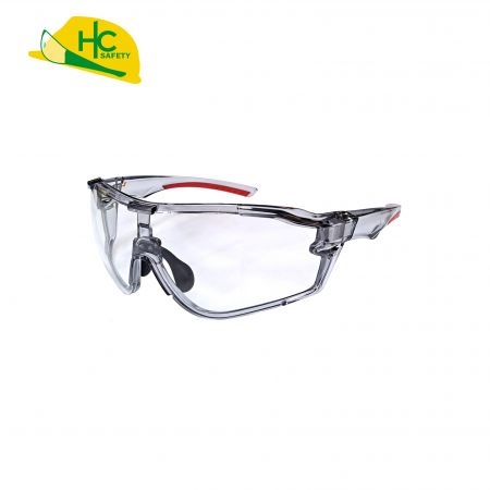 This is a pair of transparent safety glasses with red and black details, providing eye protection, suitable for use in the workplace or sports.
