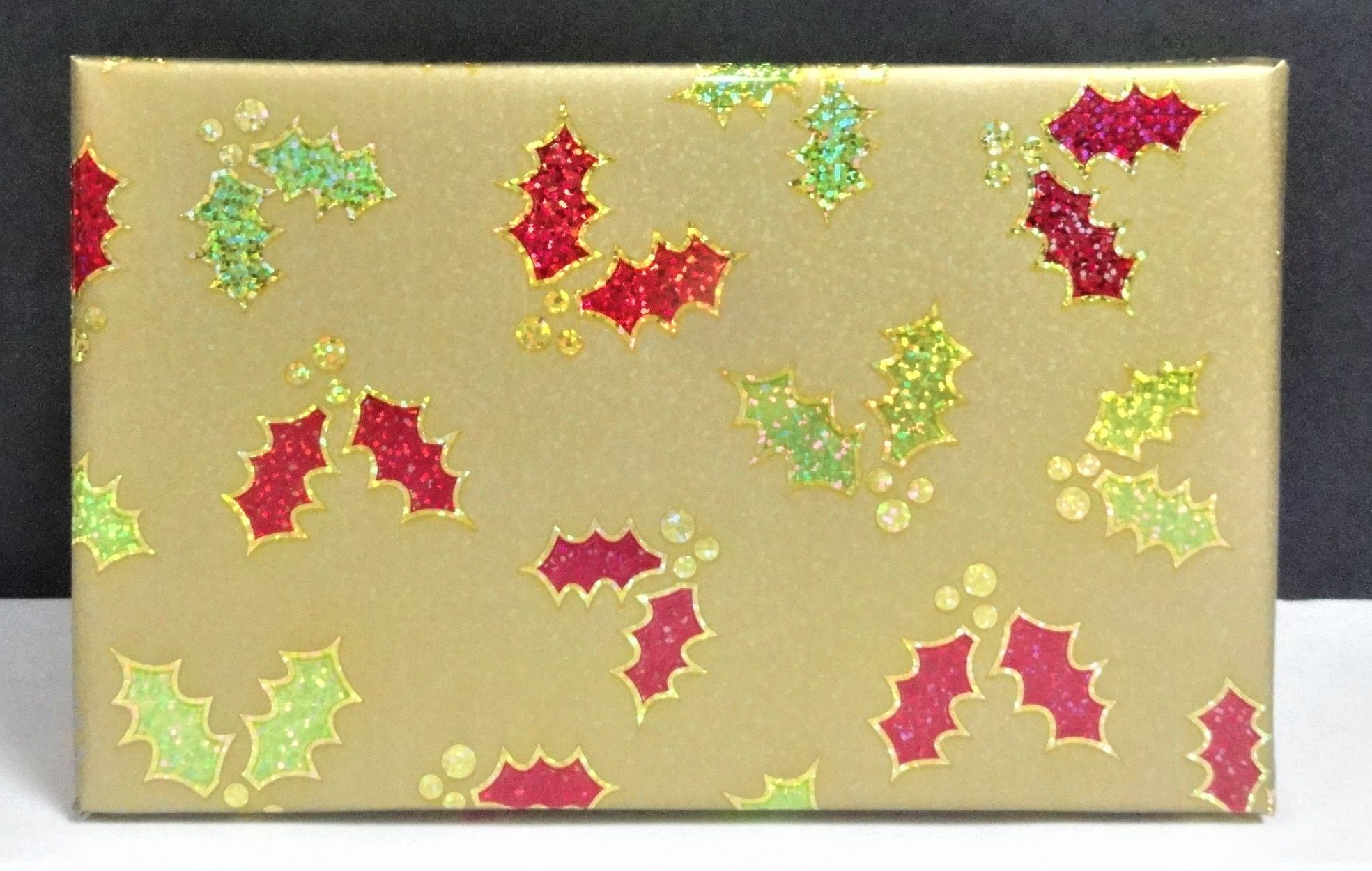 Holographic metallic paper printed with holly pattern for gift wrapping.