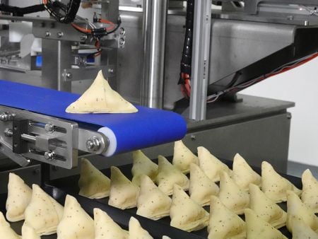 Samosas Punjabi formate sunt lăsate automat pe banda de transport