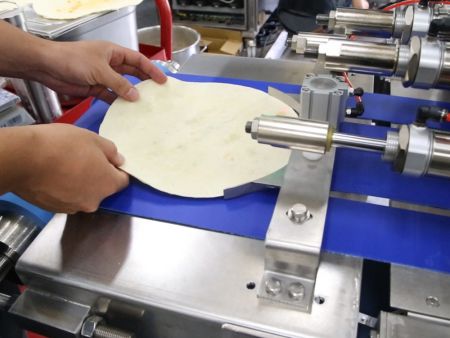 Đặt bánh tortilla lên băng chuyền bằng tay