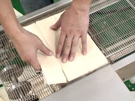 La feuille de pâte est ensuite séparée manuellement en trois parties.