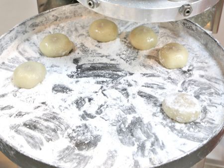 Usando un plato giratorio espolvoreado con almidón para sostener las bolas de arroz glutinoso