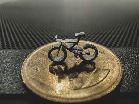 Finely crafted bicycle shape after fiber laser cutting, placed on a one-dollar coin