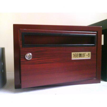 A metal mailbox with a red cherrywood grain laminated metal surface, with the mailbox door closed