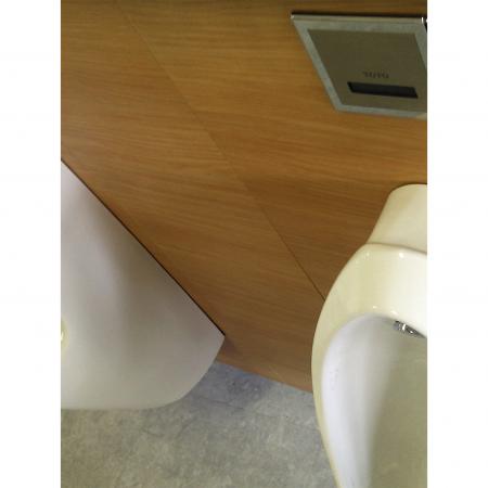 Vista frontal cercana de paneles de pared del inodoro decorados con metal laminado con grano de madera de haya