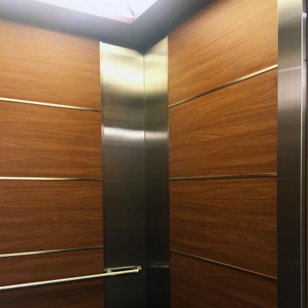 Scatto ravvicinato del lato destro di un ascensore utilizzando lastre di acciaio metallico laminato in PVC effetto noce per decorare le pareti dell'ascensore