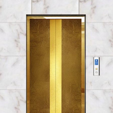 Egy modern stílusú lift, a liftajtó zárva, az ajtókeret műbronz fényes díszítéssel készült, felülete Brass Frieze laminált fémlemezekkel díszítve