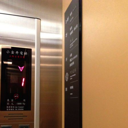 Visão em close-up de uma cabine de elevador com suas paredes decoradas com uma placa de metal laminado em Ouro Persa
