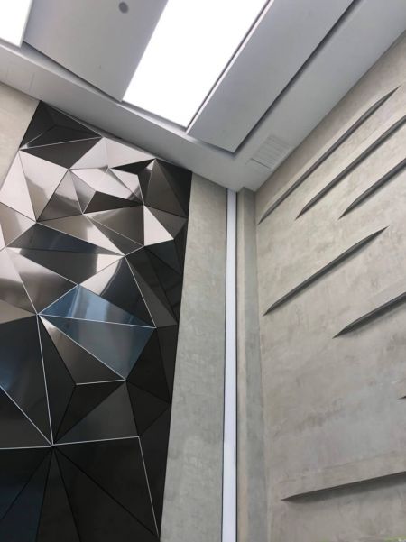 Delvis seksjon av en stilig Art deco-vegg, bruker uregelmessig formet trendy svart anti-fingerprint rustfritt stål som overflate dekorasjon