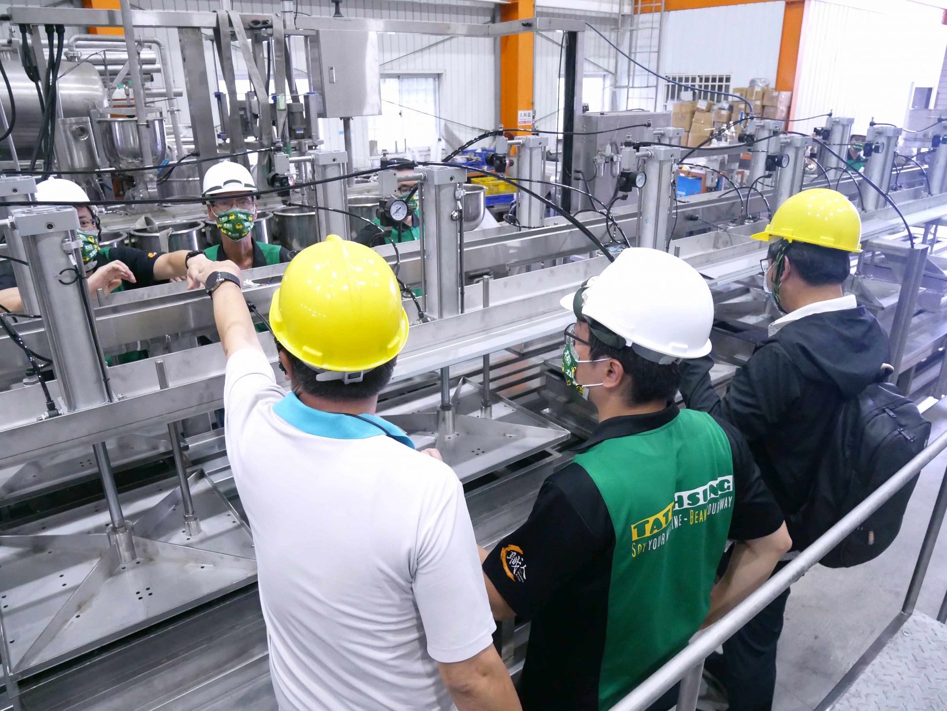 大地興工廠內部,客戶與團隊正在檢驗一台自動豆腐連續壓榨機,展現專業的品質控管流程。