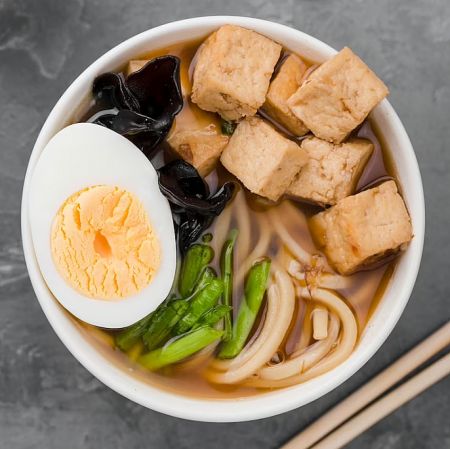 大豆蛋白與膽固醇 - 一碗含有豆腐、雞蛋和蘑菇的亞洲湯麵，展示大豆蛋白有益健康的飲食選擇