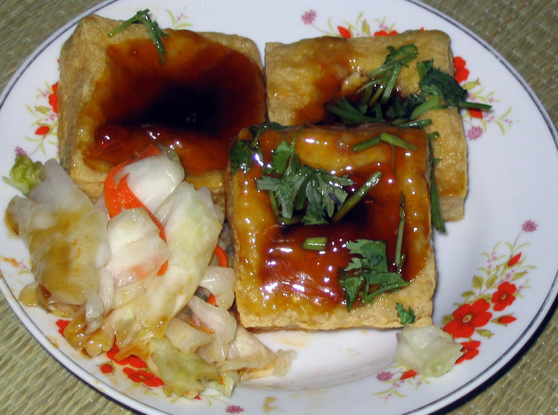 一份傳統的台灣炸臭豆腐,搭配特製醬料、香菜與泡菜。