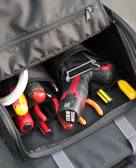 Compartimento superior con cremallera abierta con hasta 12 ranuras para almacenamiento de múltiples herramientas y bolsillo interno con cremallera.