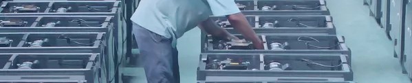 Technician performing maintenance on packaging machinery components in a factory setting.