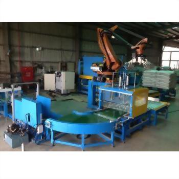 袋包飼料包自動整平堆疊機 11-3 - 一間工廠內,一套大型藍色自動化包裝生產線,包含輸送帶、包裝機和橘色機械手臂,右側可見堆疊的白色袋裝產品。