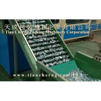 鋼瓶裝盒機 17 - 一張工業場景照片,綠色輸送帶上密密麻麻地載著大量銀色金屬零件,正穩定地向上傳送,背景可見藍色機械。